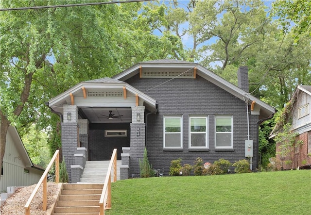 view of front of property with a front lawn, ceiling fan, a chimney, stairs, and brick siding