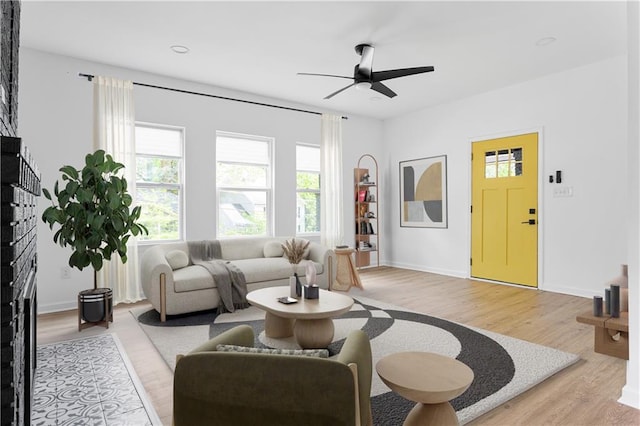 living area with a ceiling fan, baseboards, and light wood finished floors