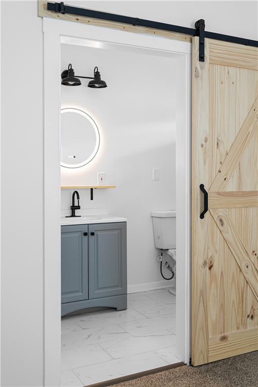 bathroom featuring vanity, baseboards, toilet, and marble finish floor