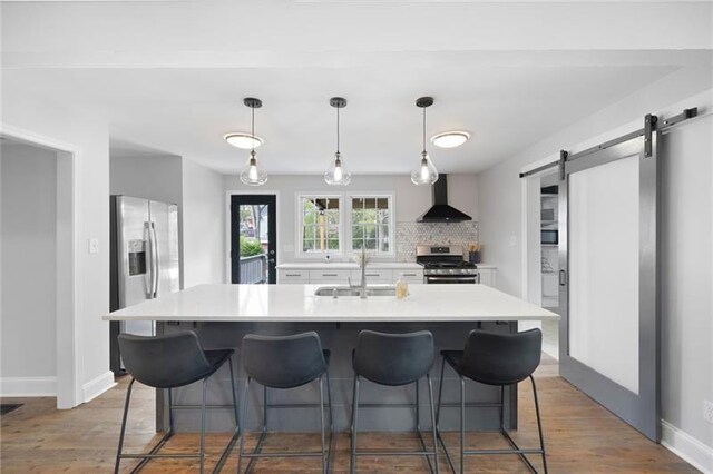 1251 Pierce Ave, Smyrna, GA 30080 - kitchen with stainless steel appliances, wall chimney exhaust hood, a barn door, and wood finished floors