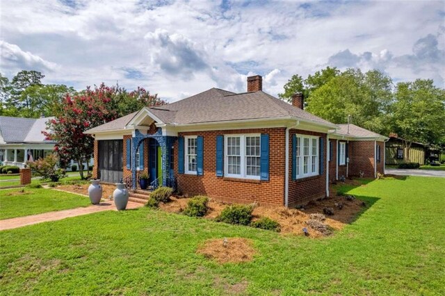 view of front of property featuring a sunroom and a front lawn