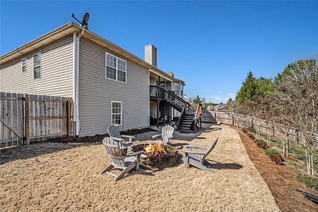 back of property featuring stairs, an outdoor fire pit, a chimney, and a fenced backyard