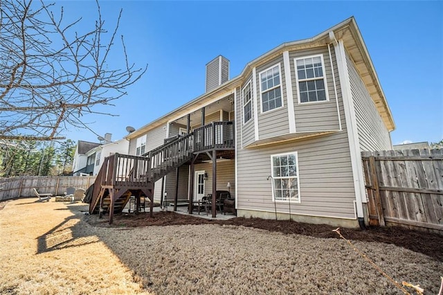 rear view of house with a patio, a fenced backyard, a chimney, stairs, and a deck