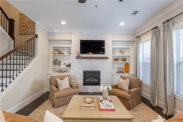 living area with visible vents, dark wood-type flooring, a healthy amount of sunlight, and ornamental molding