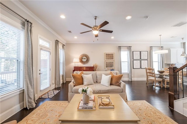 living area with wood finished floors, built in shelves, a stone fireplace, and ornamental molding