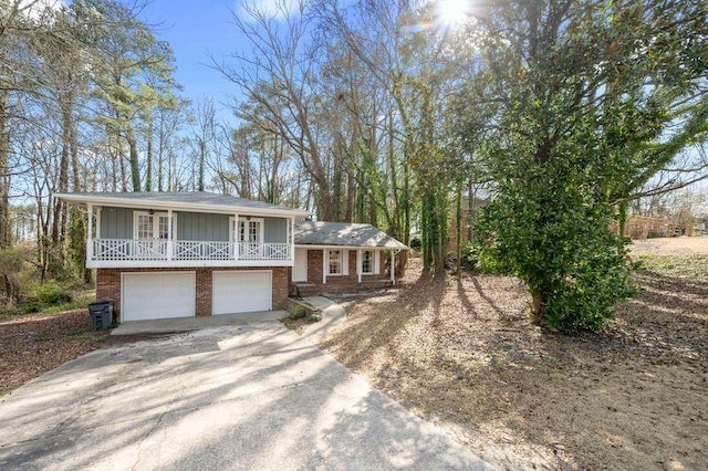 split level home with a porch, a garage, brick siding, driveway, and board and batten siding