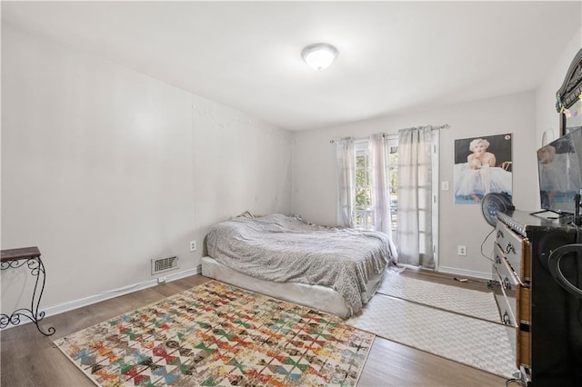 bedroom with baseboards, visible vents, and wood finished floors