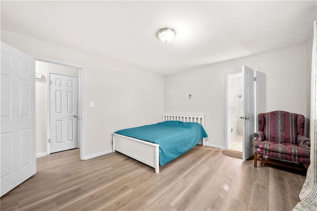 bedroom with ensuite bathroom, baseboards, and wood finished floors