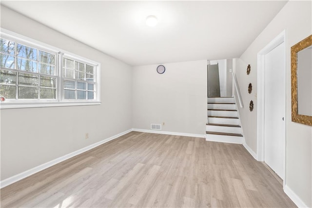 unfurnished room with light wood-type flooring, visible vents, stairs, and baseboards