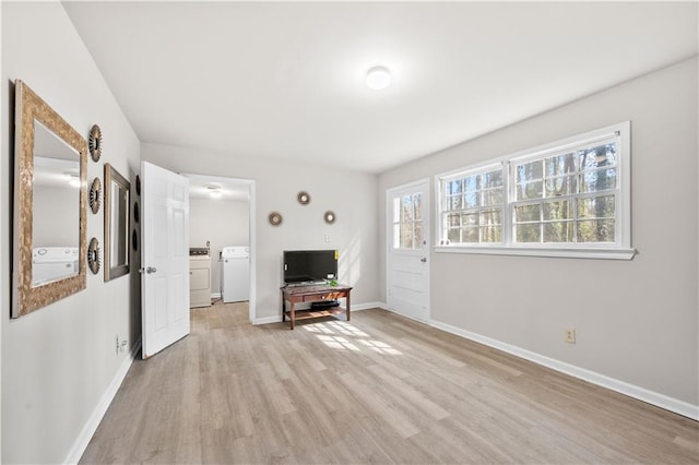 interior space featuring washer and clothes dryer, light wood-style flooring, and baseboards