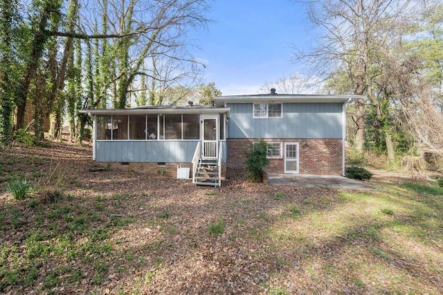 rear view of property with crawl space, a sunroom, a patio, and brick siding