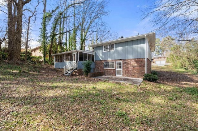 back of property featuring a sunroom, a patio area, brick siding, and a lawn