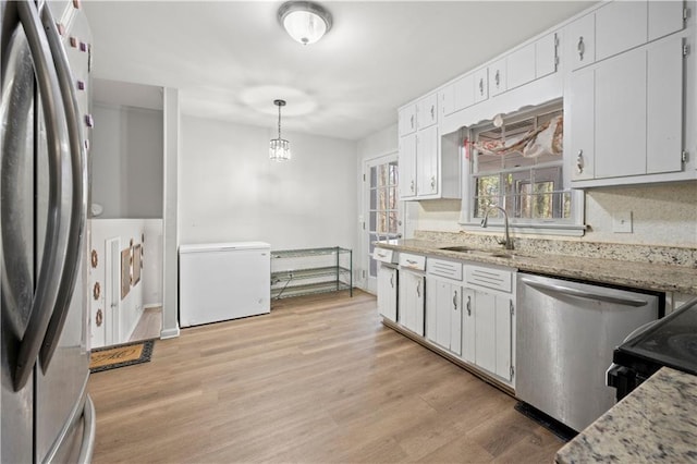 kitchen with stainless steel appliances, light wood-type flooring, white cabinets, and a sink