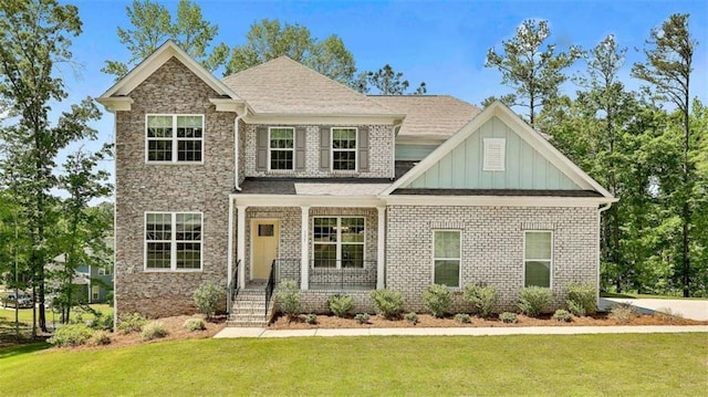 craftsman-style home featuring board and batten siding, a front yard, and brick siding