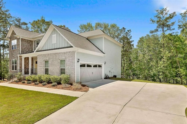 view of home's exterior with driveway, a lawn, an attached garage, board and batten siding, and brick siding