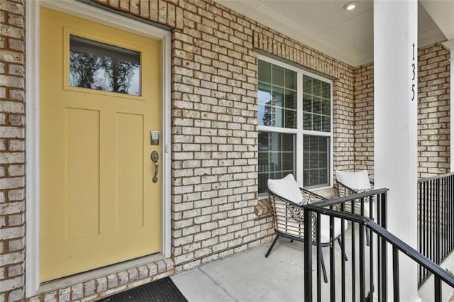 view of exterior entry with covered porch and brick siding