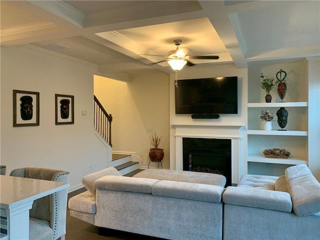 living room with coffered ceiling, ceiling fan, built in shelves, and beamed ceiling