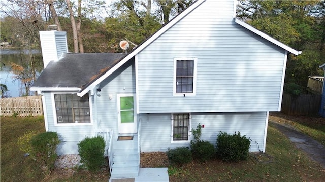 view of front of home featuring a water view, a chimney, and fence