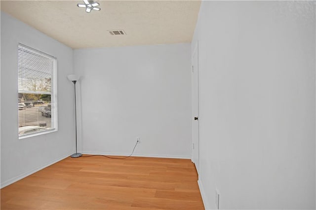 unfurnished room with light hardwood / wood-style flooring and a textured ceiling