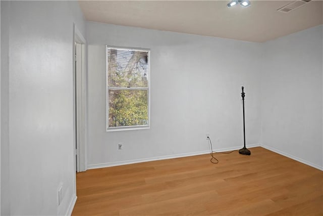 spare room featuring light wood finished floors, baseboards, and visible vents