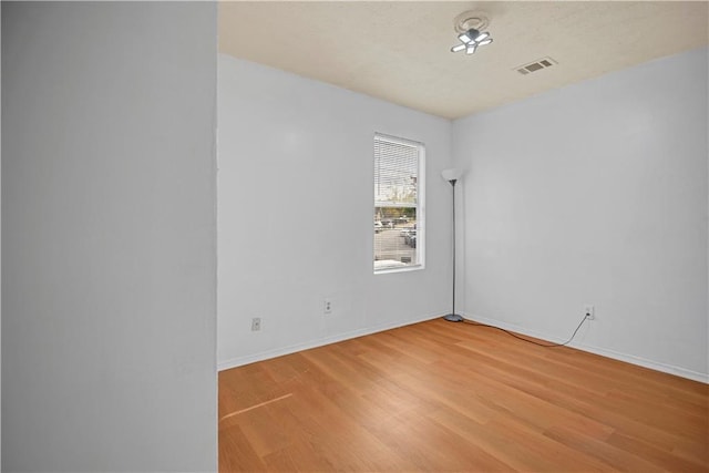 unfurnished room with light wood-style flooring, visible vents, and baseboards