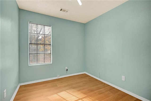 unfurnished room featuring light wood-type flooring, visible vents, and baseboards