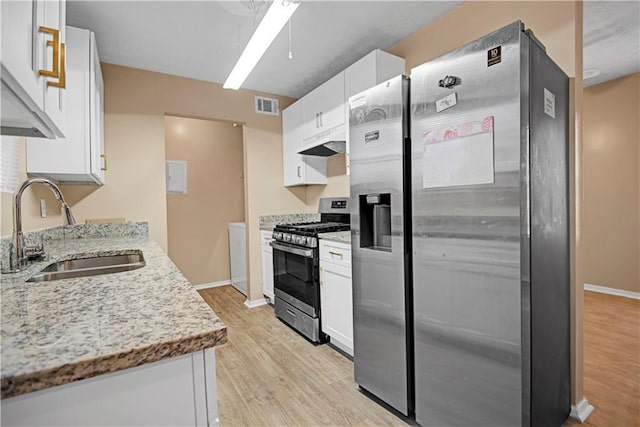 kitchen featuring under cabinet range hood, a sink, visible vents, light wood-style floors, and appliances with stainless steel finishes