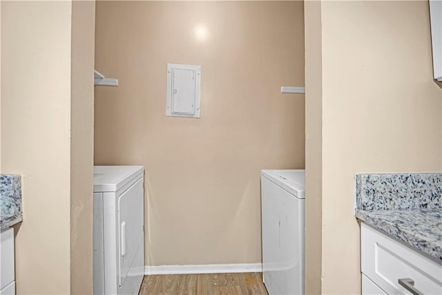 laundry room featuring light wood-style floors, laundry area, electric panel, and washer and clothes dryer