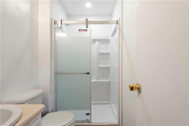 bathroom featuring toilet, a stall shower, and vanity