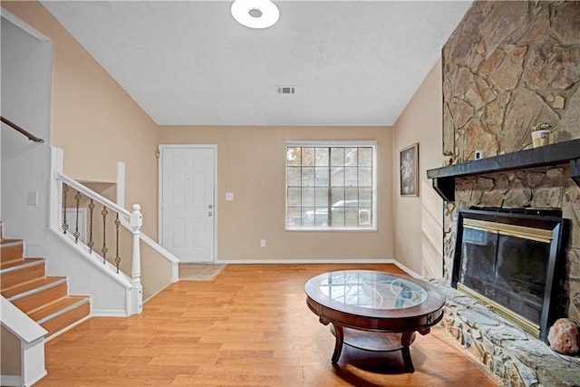 living room featuring light wood-type flooring, a fireplace, and vaulted ceiling