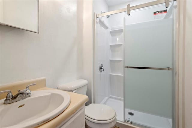 bathroom featuring toilet, a shower stall, and vanity