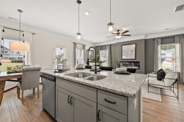 kitchen featuring visible vents, gray cabinetry, a glass covered fireplace, a sink, and dishwasher