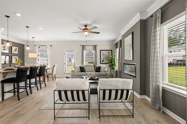 living room with baseboards, ceiling fan, light wood finished floors, and crown molding