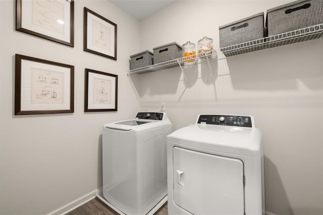 clothes washing area with washing machine and dryer, laundry area, baseboards, and wood finished floors