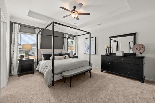 bedroom featuring light carpet, multiple windows, and a tray ceiling