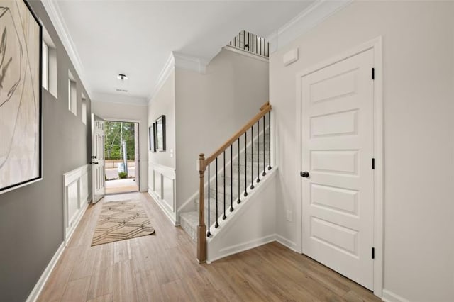 foyer with crown molding, stairway, baseboards, and wood finished floors