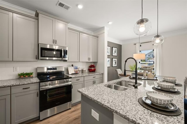 kitchen with gray cabinetry, stainless steel appliances, a sink, ornamental molding, and tasteful backsplash