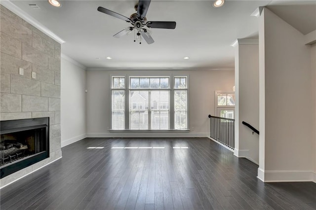 unfurnished living room with crown molding, a tile fireplace, and dark hardwood / wood-style flooring