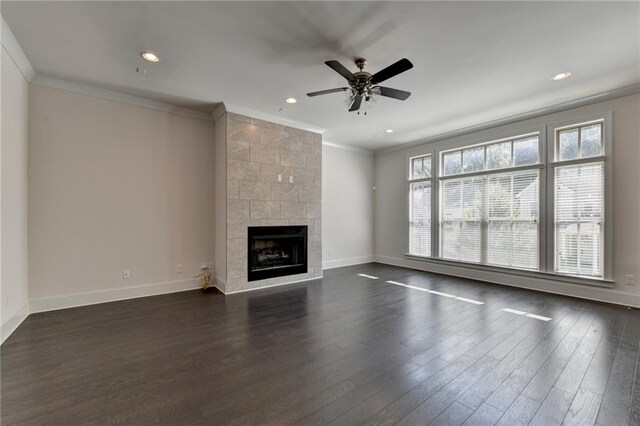 unfurnished living room featuring ceiling fan, dark hardwood / wood-style floors, ornamental molding, and a tile fireplace