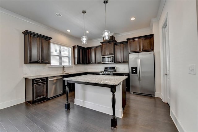 kitchen with crown molding, dark hardwood / wood-style flooring, hanging light fixtures, appliances with stainless steel finishes, and a center island