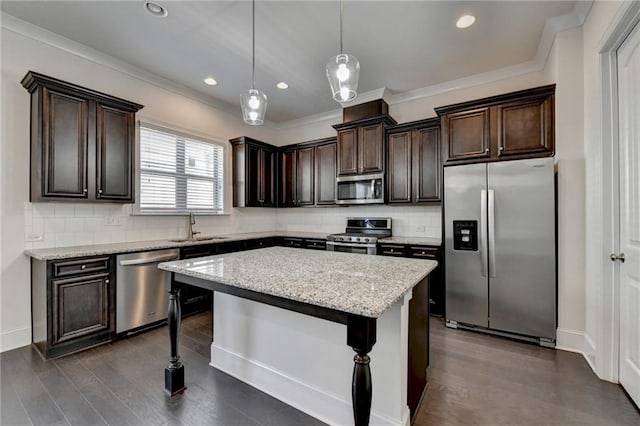 kitchen with pendant lighting, appliances with stainless steel finishes, backsplash, and a center island