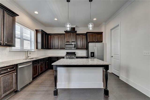 kitchen with tasteful backsplash, stainless steel appliances, hanging light fixtures, a kitchen bar, and a center island