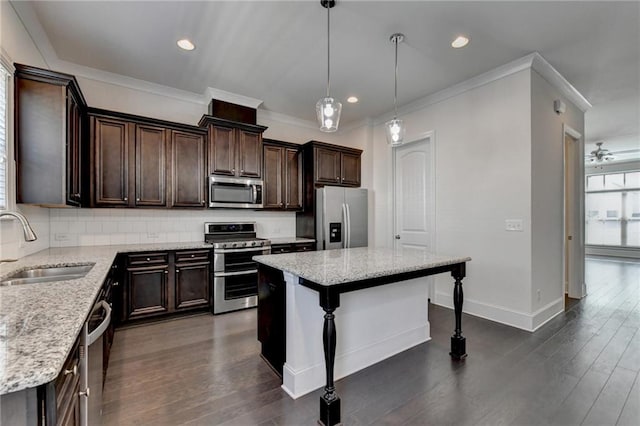 kitchen with pendant lighting, a kitchen island, dark wood-type flooring, sink, and appliances with stainless steel finishes