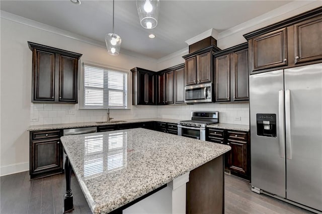 kitchen featuring pendant lighting, dark wood-type flooring, stainless steel appliances, a center island, and decorative backsplash