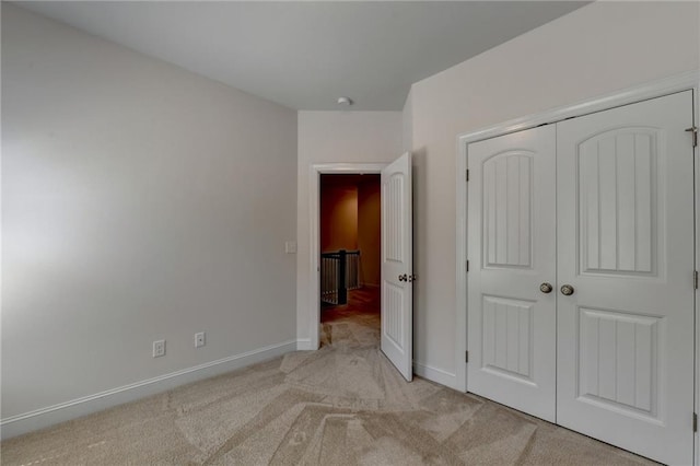 unfurnished bedroom featuring light colored carpet and a closet