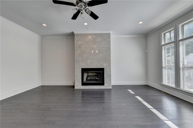 unfurnished living room featuring a tiled fireplace, plenty of natural light, and dark hardwood / wood-style floors