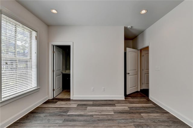 unfurnished bedroom with connected bathroom and dark wood-type flooring