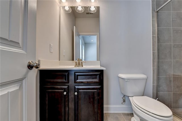 bathroom featuring tile patterned flooring, tiled shower, vanity, and toilet