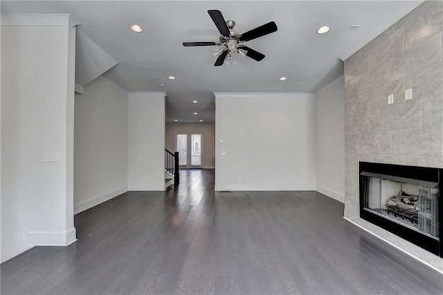 unfurnished living room with dark wood-type flooring, tile walls, ceiling fan, and a tile fireplace