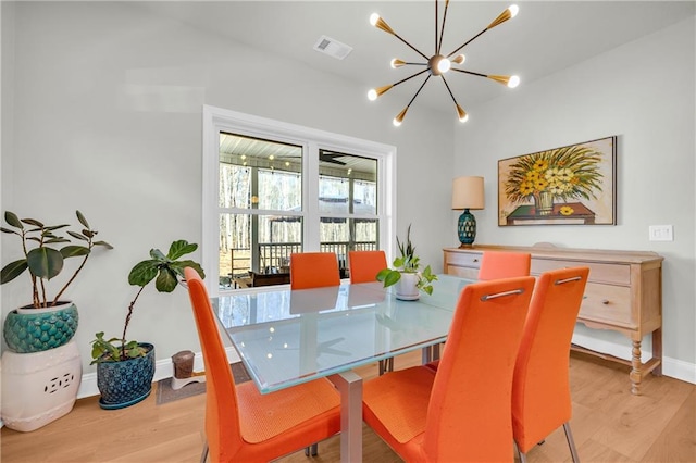 dining space featuring light wood-type flooring and an inviting chandelier